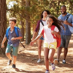 Young boy and girl happily running through the woods